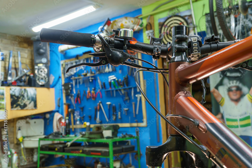 Mountain bike in the workshop on the background of a stand with tools. Bicycle repair before competitions. Safe use of a serviceable bicycle. Maintenance of components and assemblies.