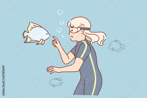 Little girl diver swims under in lake among fishes exploring underwater world during summer trip