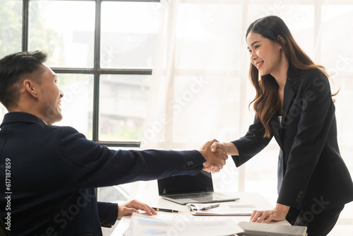 Bilde på lerret Happy young asian business man and woman shaking hands to congratulate successfu