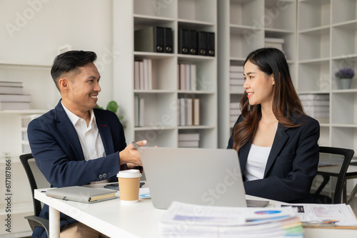 Smart and professional male manager working with his female assistant. check financial reports Analyze financial data with graph papers and laptop with desk.