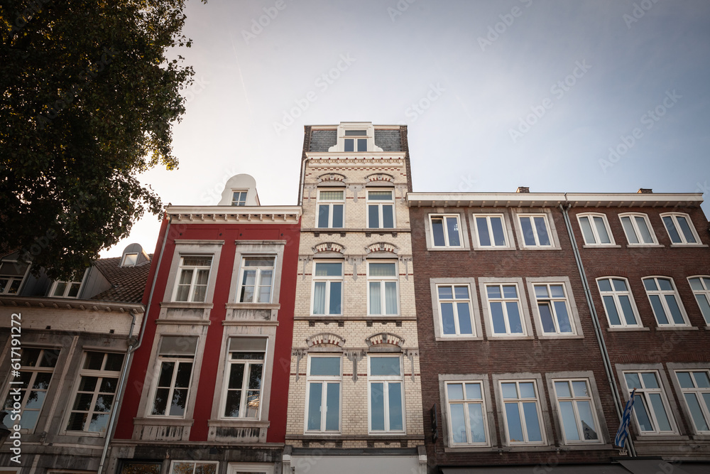 Typical facades of dutch architecture in the city center of Maastricht, Netherlands, with residential buildings, facades of red brick, stone and flats.