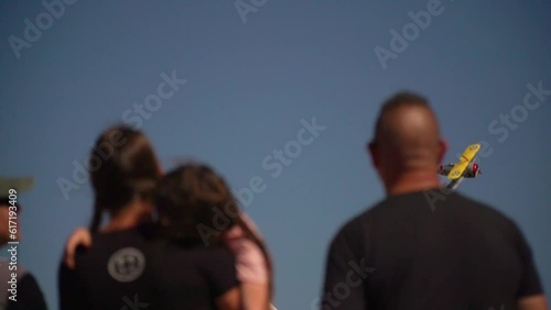 Old yellow winged biplane flies behind crowd of people