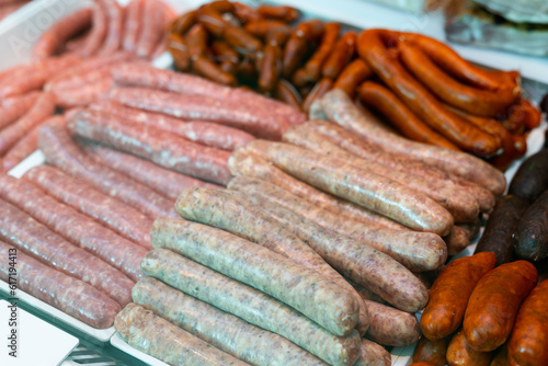 Different types of meat sausages laid out on counter in butcher shop..