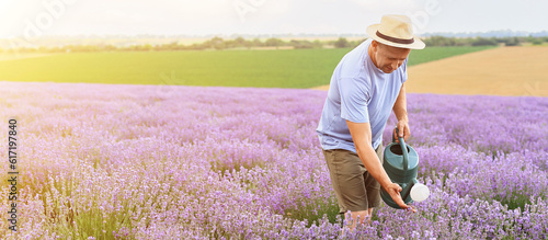Fototapeta Naklejka Na Ścianę i Meble -  Male farmer with watering can in lavender field