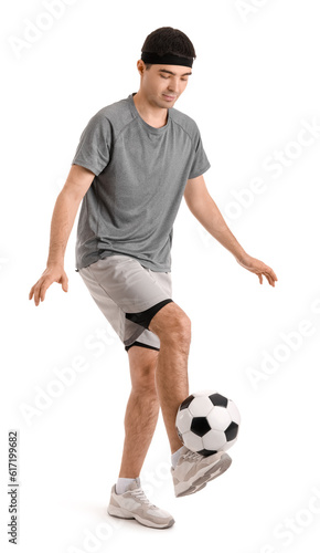 Sporty young man playing with soccer ball on white background. Balance concept