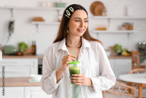 Young woman with glass of vegetable juice in kitchen
