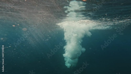 One man jumping and entering the water of the blue sea enjoying and having fun lifestyle. Under water view of male jumping from a cliff to the ocean