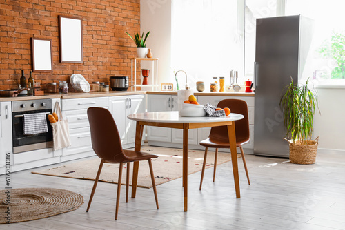 Interior of kitchen with stylish fridge, counters, table and chairs