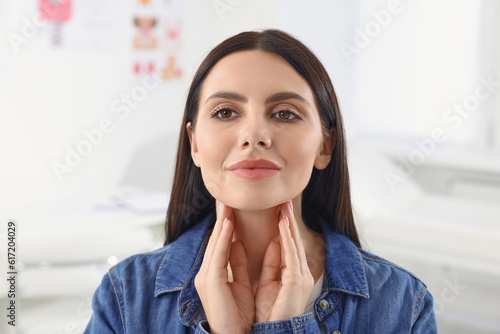 Endocrine system. Young woman doing thyroid self examination indoors photo