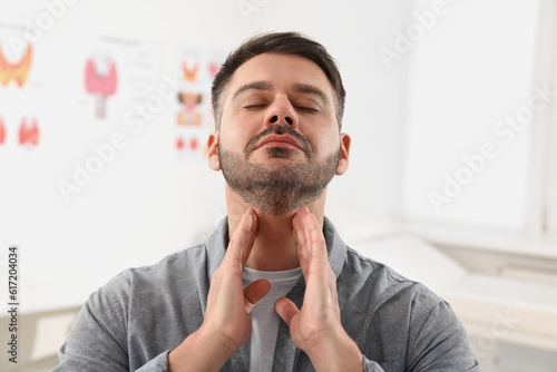 Endocrine system. Man doing thyroid self examination indoors