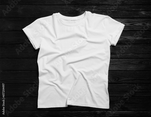 Stylish white t-shirt on black wooden background, top view