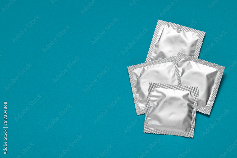 Packaged condoms on light blue background, top view with space for text. Safe sex