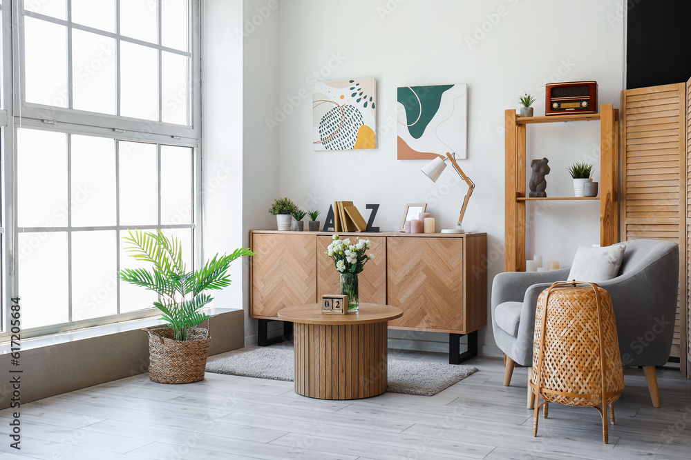 Fototapeta premium Interior of living room with drawers, shelving unit and armchair
