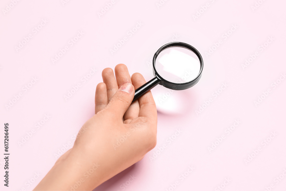 Female hand with magnifier on pink background Female hand with magnifier on pink background