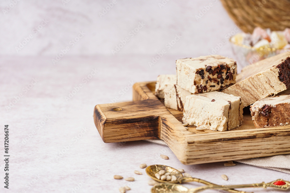 Wooden board with pieces of tasty marble halva on light background Wooden board with pieces of tasty marble halva on light background