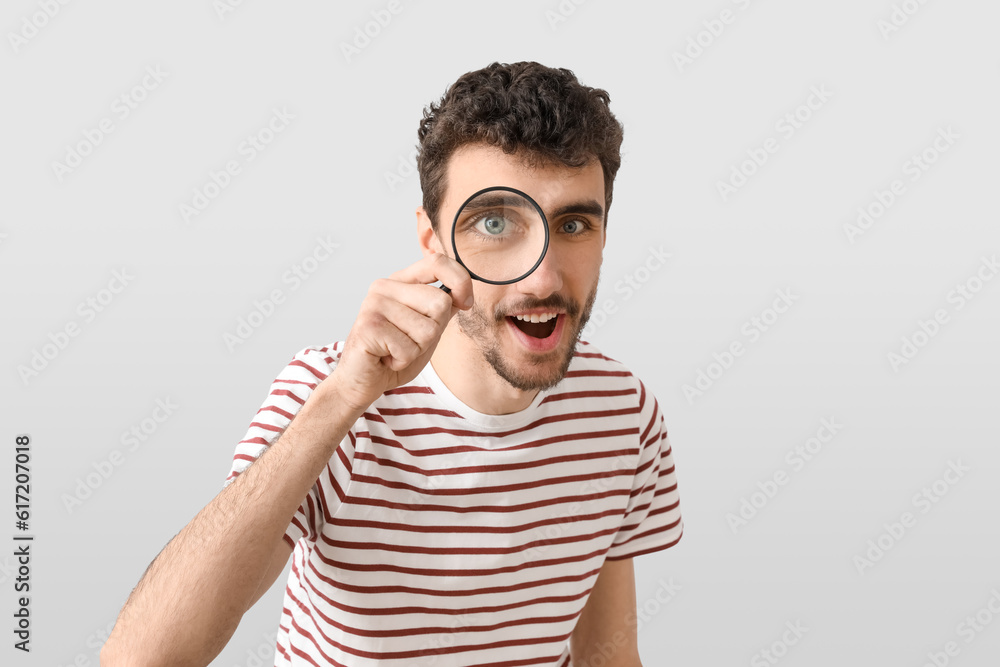 Happy young man with magnifier on light background Happy young man with magnifier on light background