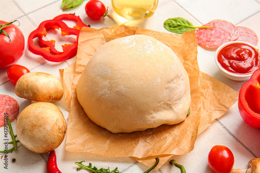 Raw dough and ingredients for preparing pizza on white tile background Raw dough and ingredients for preparing pizza on white tile background