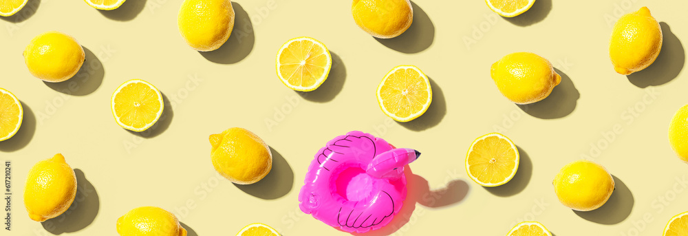 Summer concept with a pink flamingo float and lemons - flat lay