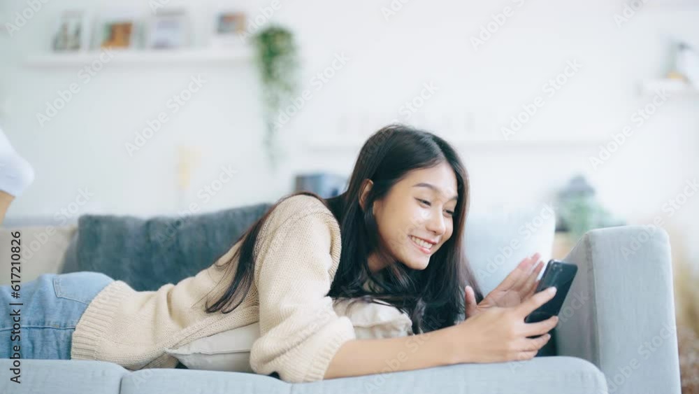 Happy Young Asian Woman Relaxing at Home. Smiling on Sofa with Mobile Smartphone. Video Call with Friend Happy Young Asian Woman Relaxing at Home. Smiling on Sofa with Mobile Smartphone. Video Call with Friend