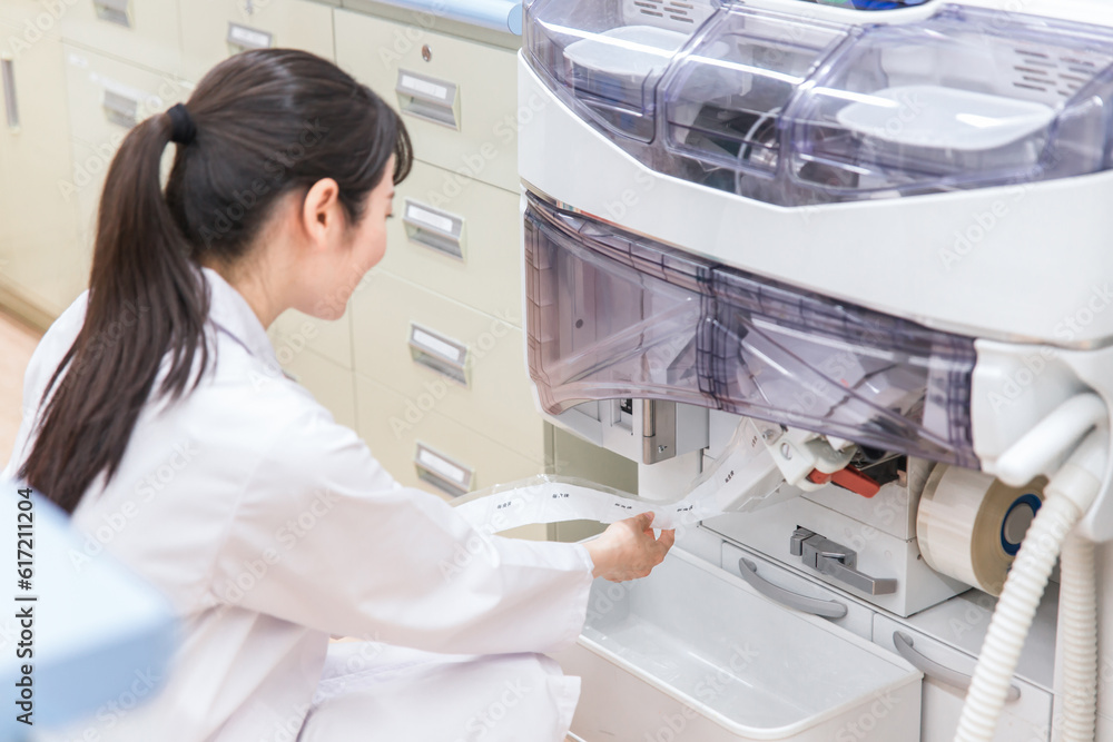 Fototapeta premium 薬局・ドラッグストアで自動分包機を使って粉薬・調剤・処方箋を作る薬剤師 