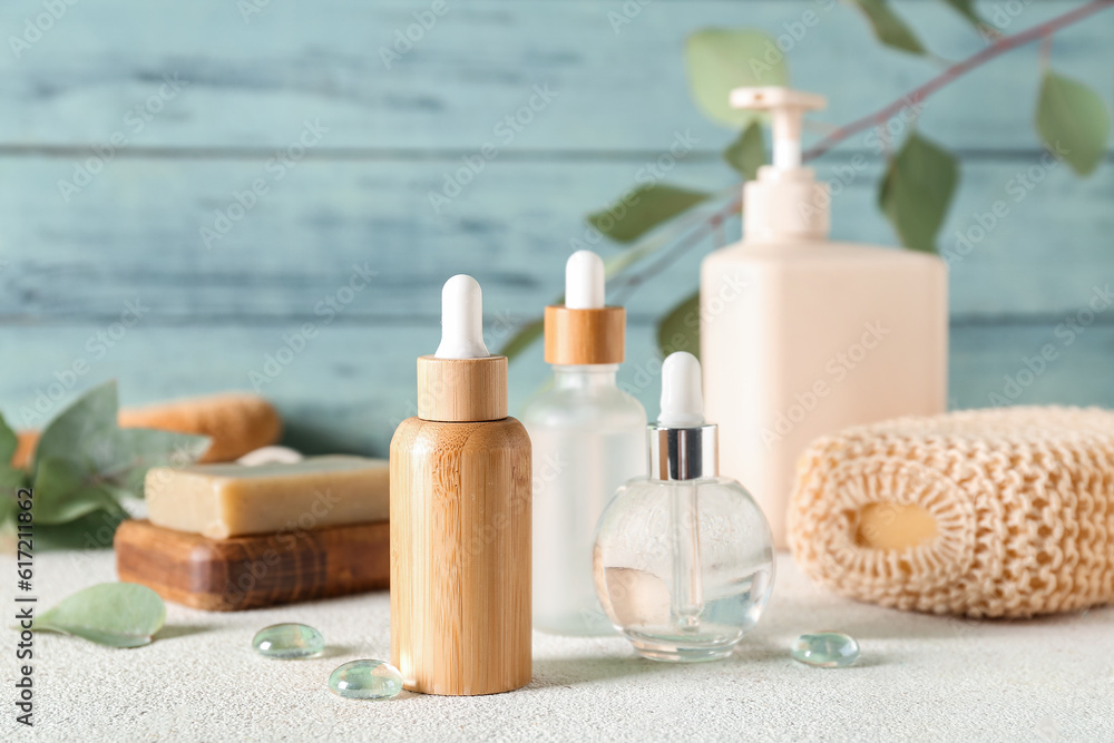 Bottles of cosmetic products, soap and sponge on color background, closeup Bottles of cosmetic products, soap and sponge on color background, closeup
