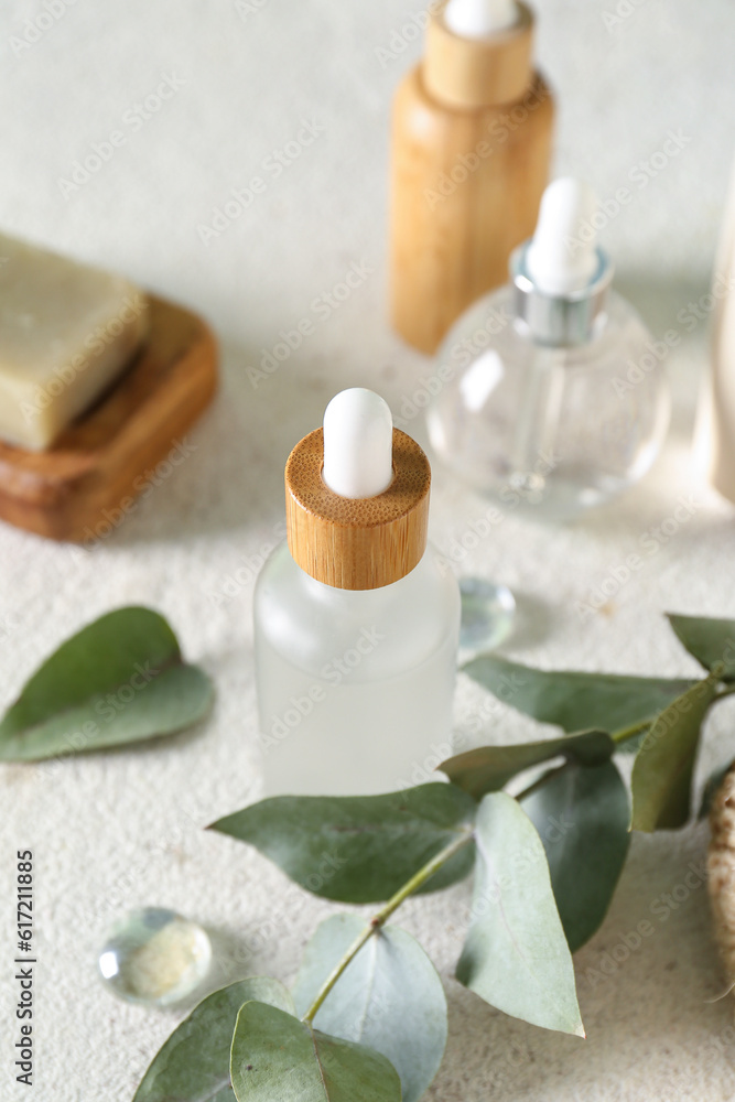 Bottles of cosmetic products, soap and branch on light background, closeup Bottles of cosmetic products, soap and branch on light background, closeup