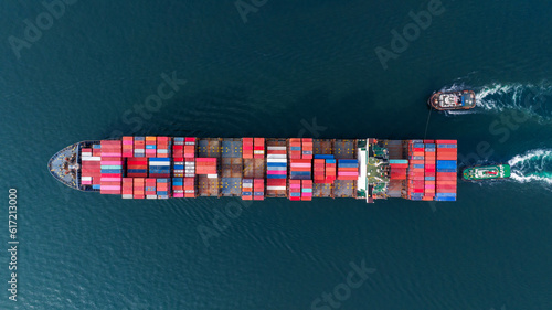 Aerial top view of cargo ship carrying container and running with tug boat for import export goods from cargo yard port to custom ocean concept freight shipping by ship .