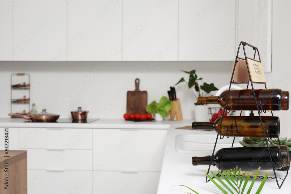Rack with wine bottles on white countertop in modern kitchen Rack with wine bottles on white countertop in modern kitchen