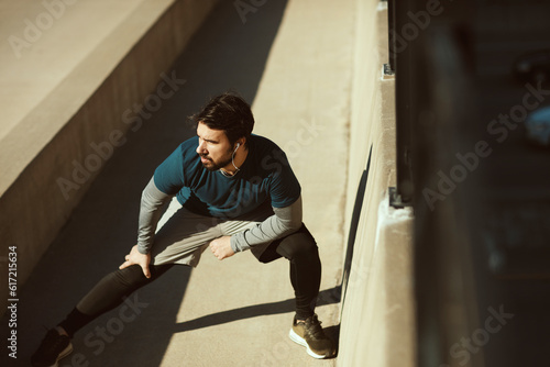 Young adult man stretching after working out in the city
