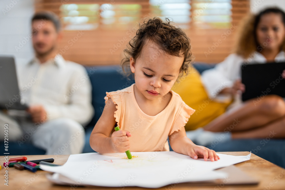 African kid painting on paper with parents behind indoor in house. African kid painting on paper with parents behind indoor in house.