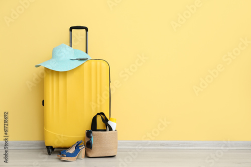 Suitcase with passport and beach accessories on yellow background. Travel concept