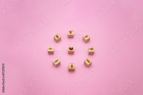 立体的な人の輪のウッドキューブがハートを囲んでいるピンクの背景 © KIKORI