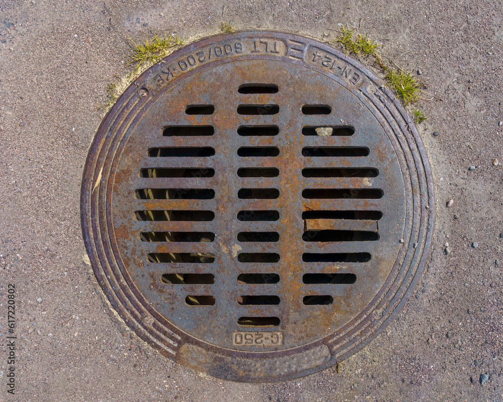 Round metal storm drain cover on asphalt, top view Round metal storm drain cover on asphalt, top view