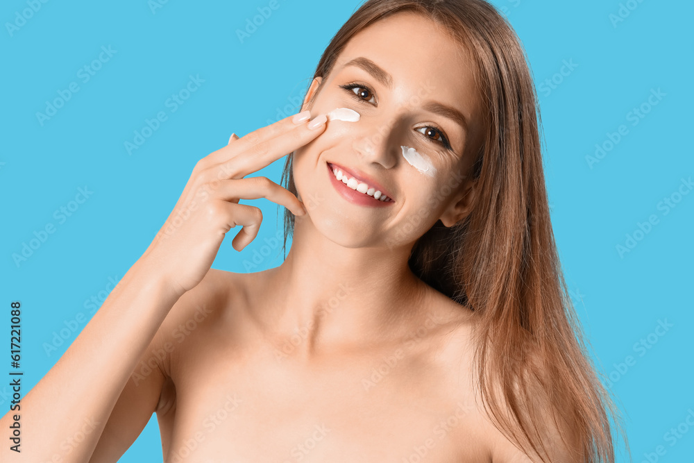 Young woman applying sunscreen cream on blue background, closeup Young woman applying sunscreen cream on blue background, closeup