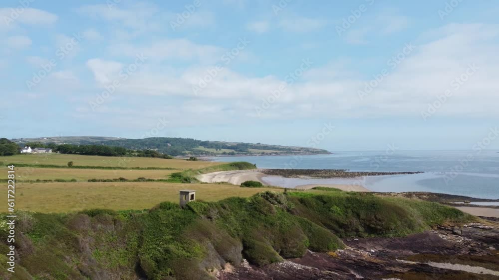 Traeth Lligwy crumbling shoreline aerial view pull back establishing scenic green Welsh weathered coastline Traeth Lligwy crumbling shoreline aerial view pull back establishing scenic green Welsh weathered coastline