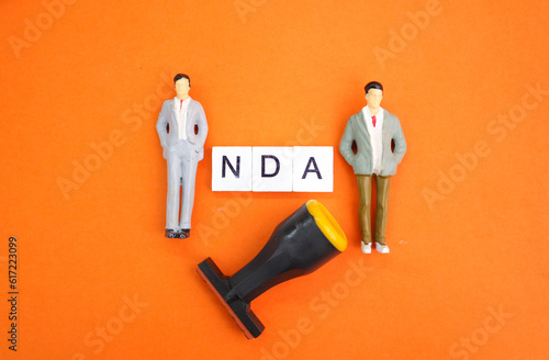 miniature people with the letters NDA or the word Non-Disclosure Agreement. the concept of consent. the concept of agreement photo