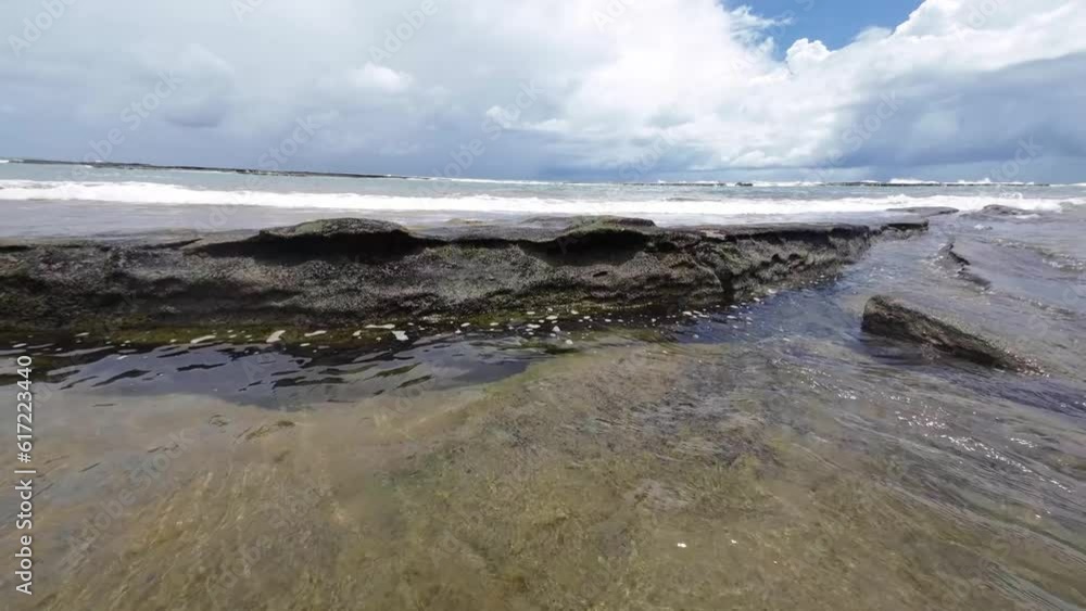 Beautiful landscape shot of small waves crashing over large rocks of the Tibau do Sul beach near Pipa, Brazil in Rio Grande do Norte during a cloudy summer day. Beautiful landscape shot of small waves crashing over large rocks of the Tibau do Sul beach near Pipa, Brazil in Rio Grande do Norte during a cloudy summer day.