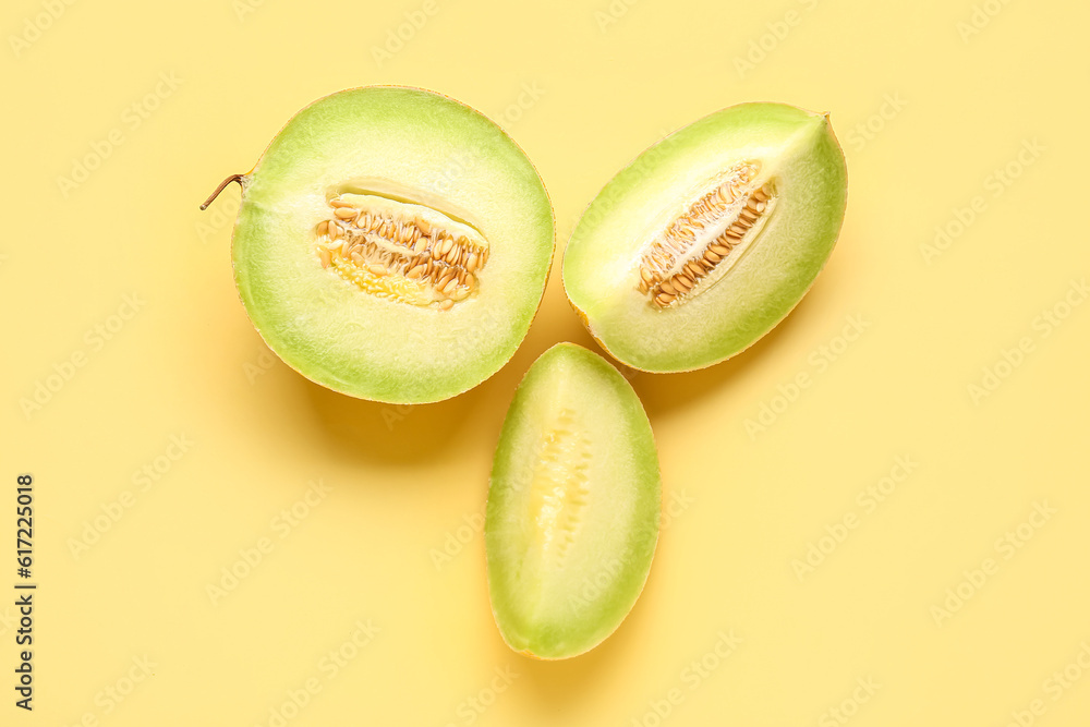 Half of sweet melon with pieces on yellow background Half of sweet melon with pieces on yellow background
