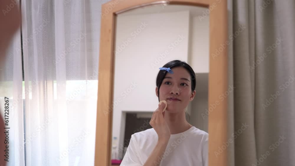 鏡を見ながらファウンデーションを塗る若い女性 鏡を見ながらファウンデーションを塗る若い女性