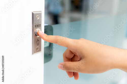 Closeup icon hand press on exit push button with finger point to digital door security in building. Safety door in office building for entrance-exit security system.