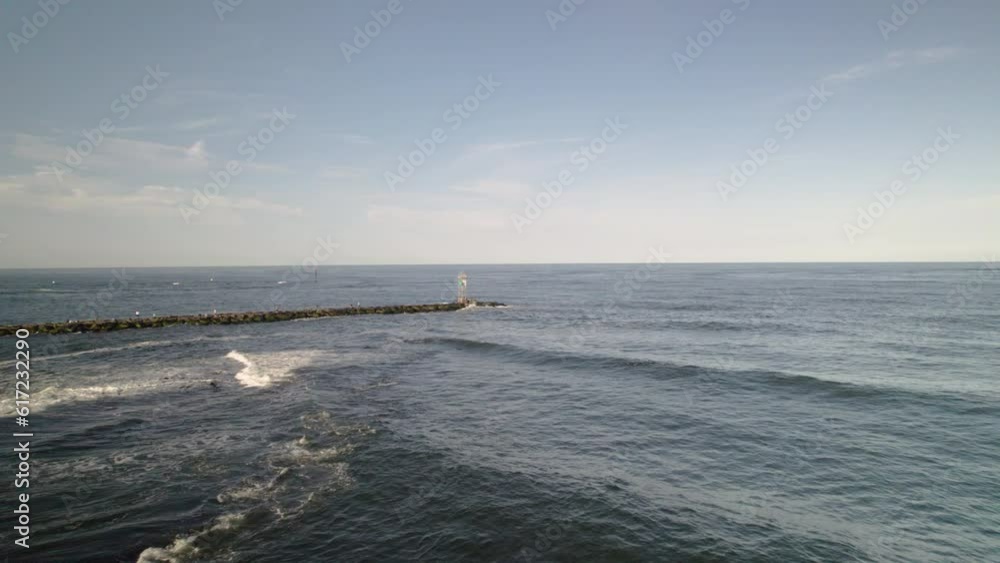 FAST Beach drone aerial shot moving along rocks towards jetty and light house tower marking boat channel FAST Beach drone aerial shot moving along rocks towards jetty and light house tower marking boat channel