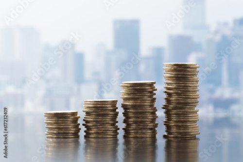 Increasing business income and salary. Successful business. Stack of coins on cityscape background.