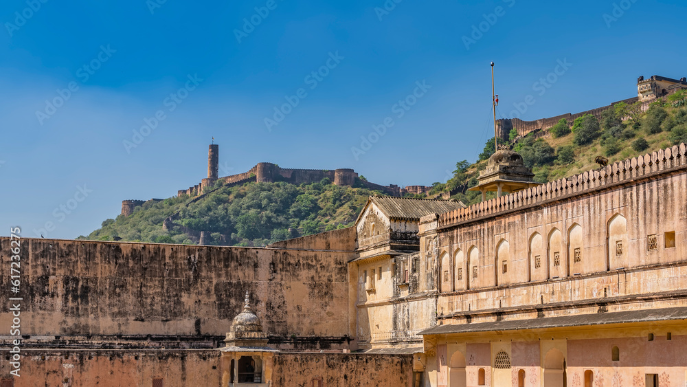 Weathered sandstone walls of the ancient Amber Fort. There is a protective fortress wall on the ridge of the mountain. Blue sky. Jaipur. India. 