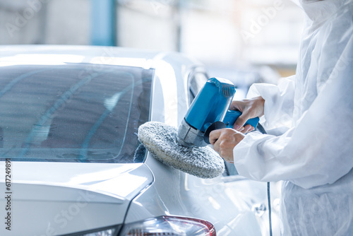 Close-up shot of a professional car painter working with grinding tools, polishing car parts, painting service, repairing a car after an accident