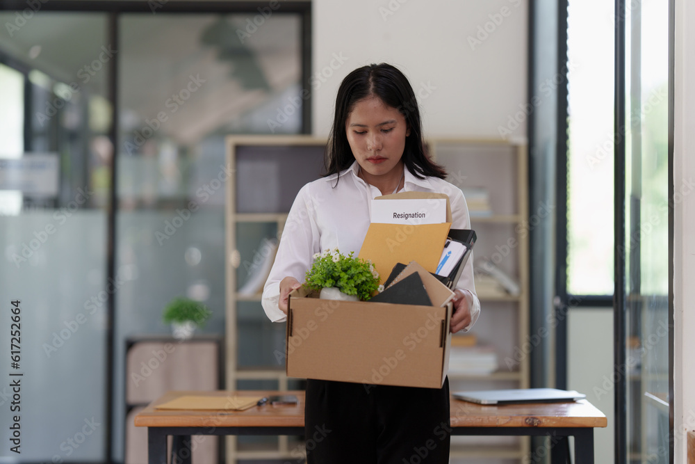 Resignation concept. Fired employee holding box of belongings in an office Resignation concept. Fired employee holding box of belongings in an office