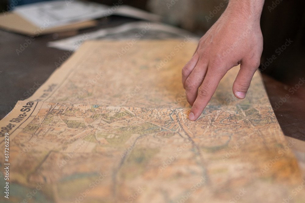 a person's finger pointing on the old map to go to the destination a person's finger pointing on the old map to go to the destination