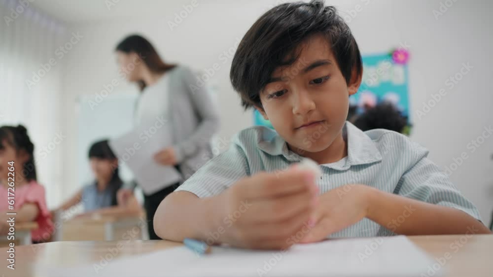 Group diverse students learning with woman teacher at elementary school. Young teacher woman handing out papers for exams to children sit on desk in classroom at school. Student examination concept Group diverse students learning with woman teacher at elementary school. Young teacher woman handing out papers for exams to children sit on desk in classroom at school. Student examination concept
