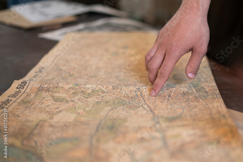 a person's finger pointing on the old map to go to the destination