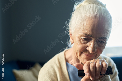 Tableau sur toile Pensive senior woman with grey hair keeping hand on handle of walking cane while