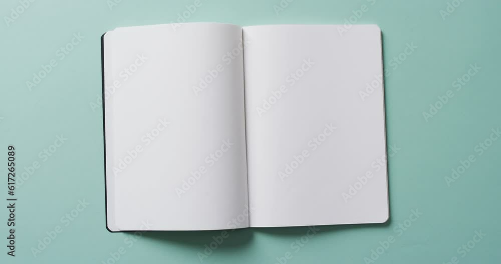 Close up of open blank book with copy space on green background in slow motion Close up of open blank book with copy space on green background in slow motion